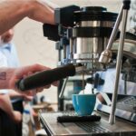 Commercial espresso machine preparing coffee in a busy café during morning service hours