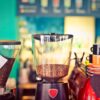Commercial espresso machine being used in a small café with professional barista preparing coffee drinks