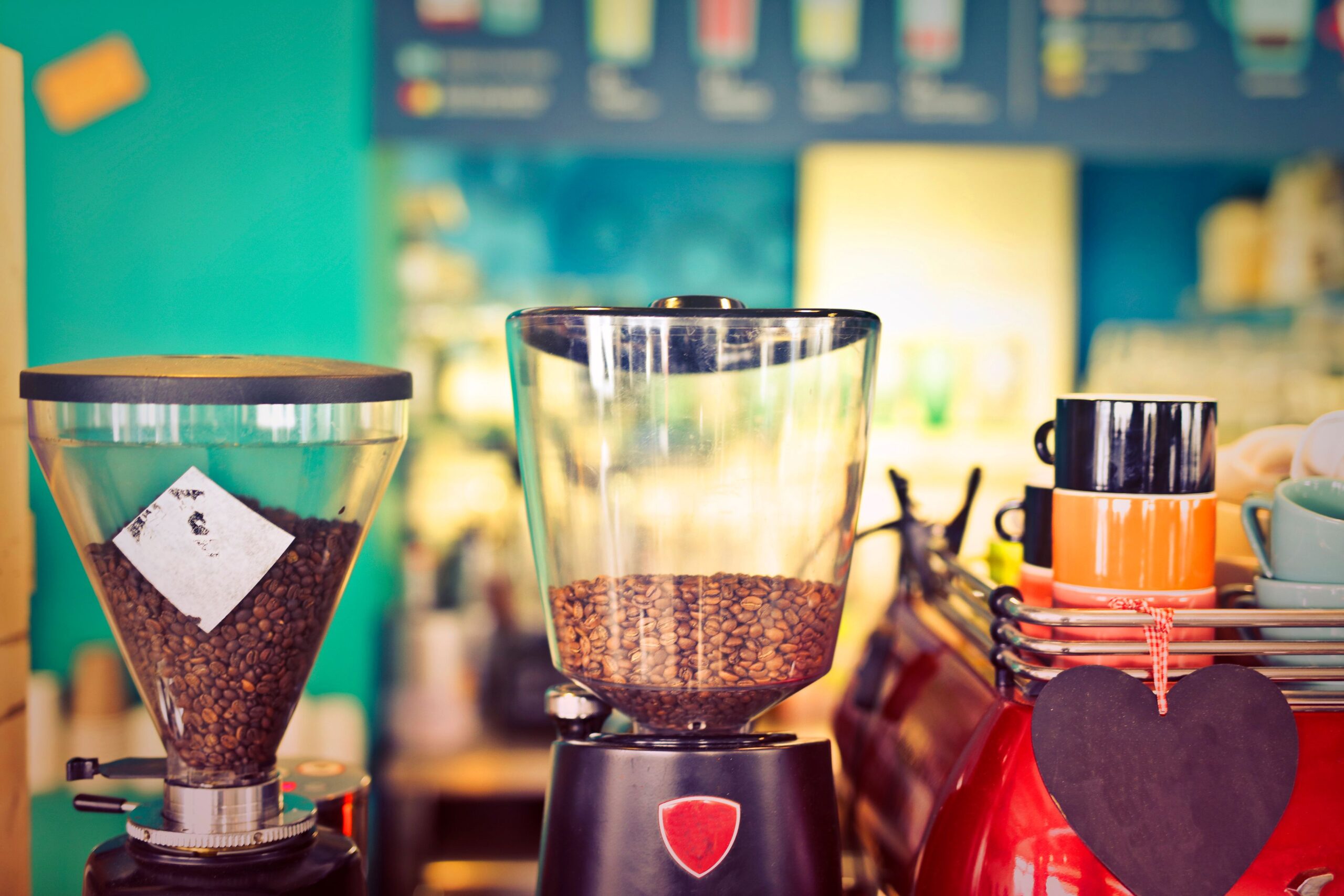 Commercial espresso machine being used in a small café with professional barista preparing coffee drinks