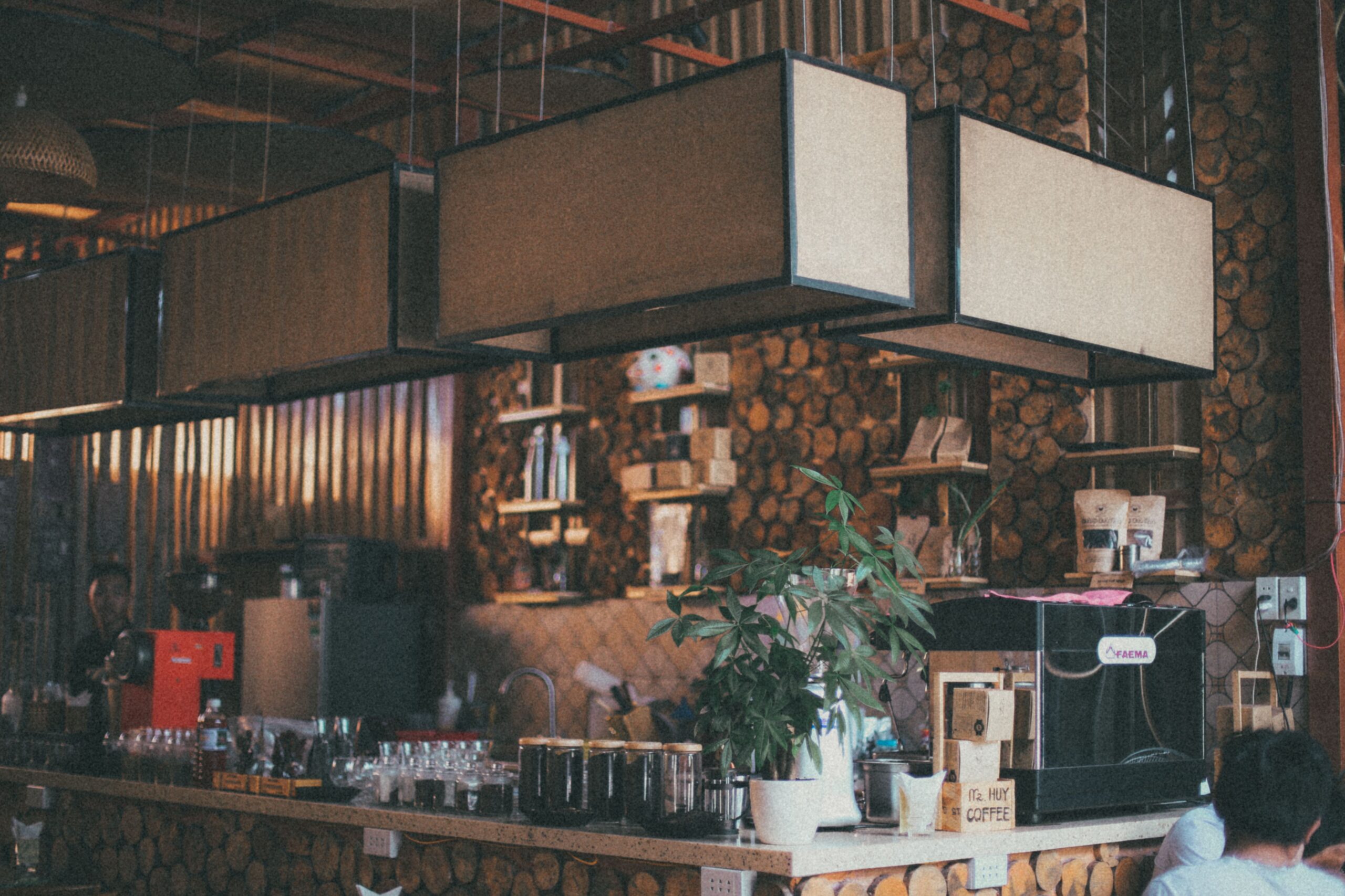 Coffee shop owner calculating the return on investment of a commercial espresso machine while reviewing café operating costs and daily coffee sales.