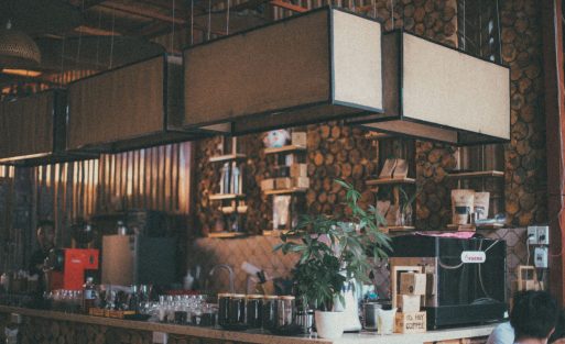 Coffee shop owner calculating the return on investment of a commercial espresso machine while reviewing café operating costs and daily coffee sales.