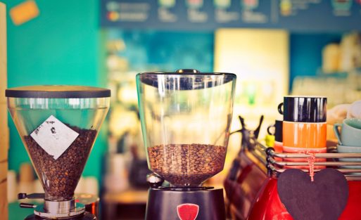 Commercial espresso machine being used in a small café with professional barista preparing coffee drinks